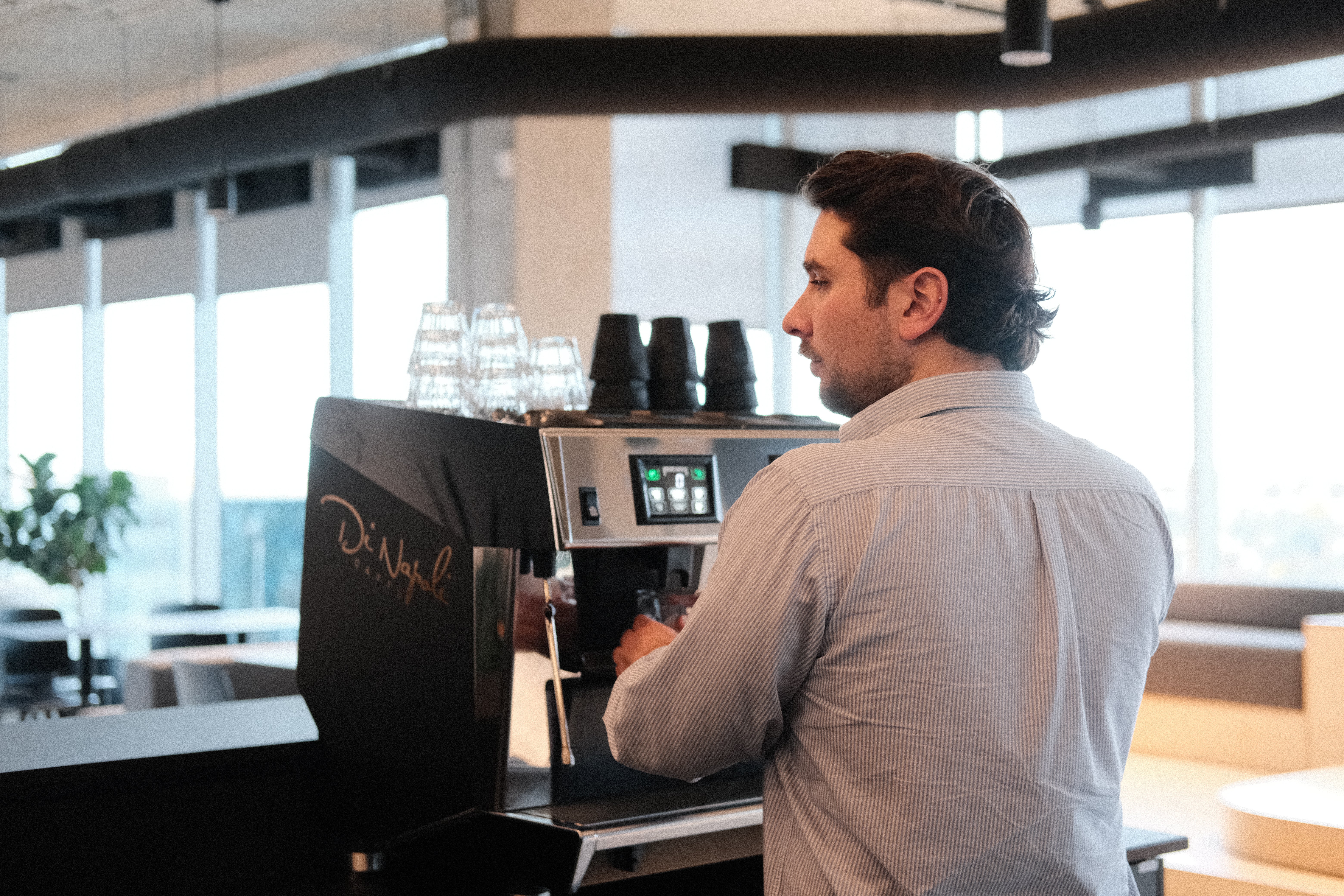 Homme préparant un café à une machine à espresso Di Napoli Caffè dans un café lumineux