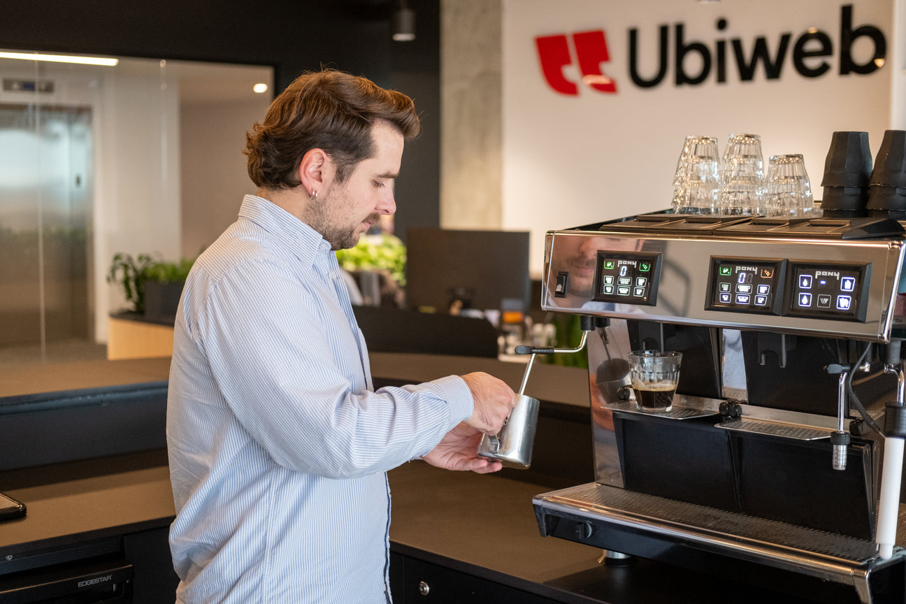 Homme préparant un café latté avec une machine à espresso professionnelle dans les bureaux d'Ubiweb