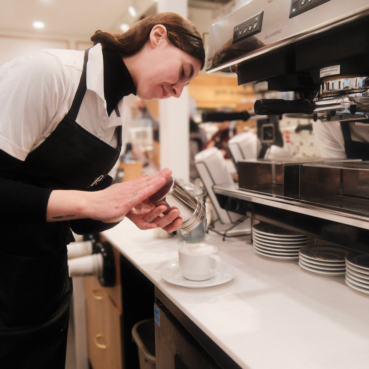 Barista préparant un café derrière une machine à espresso commerciale dans un restaurant
