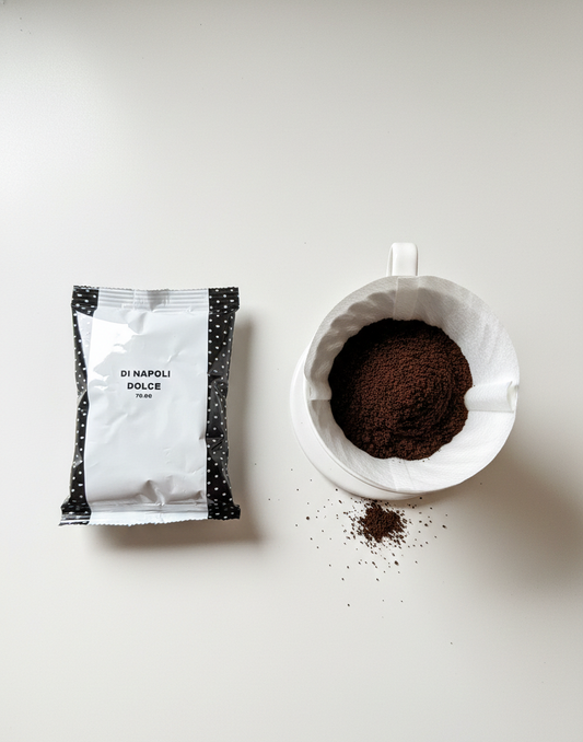 Sachet de café moulu Di Napoli Dolce à côté d'une tasse remplie de café moulu, vu de haut